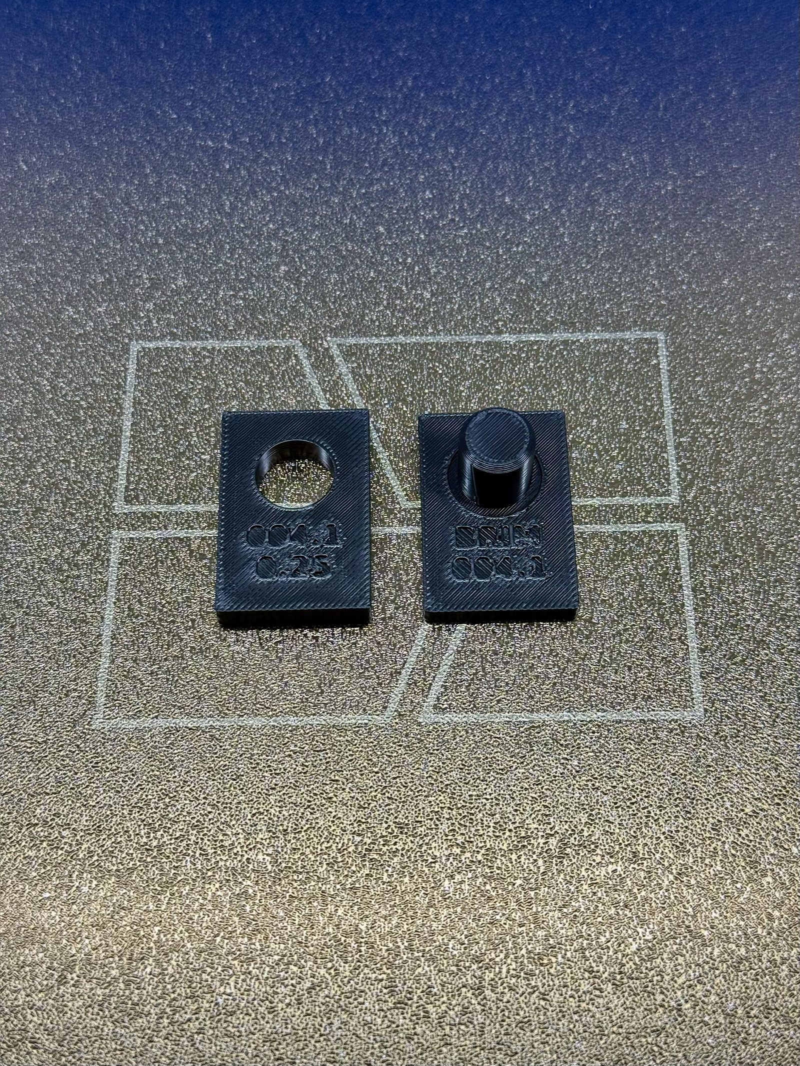 The two parts of iteration 1 side by side before assembly: the gauge block with its 12.5 mm bore, debossed 004.1 and 0.25, and the plate with its 12 mm peg and lead-in chamfer, debossed BRIM 004.1.