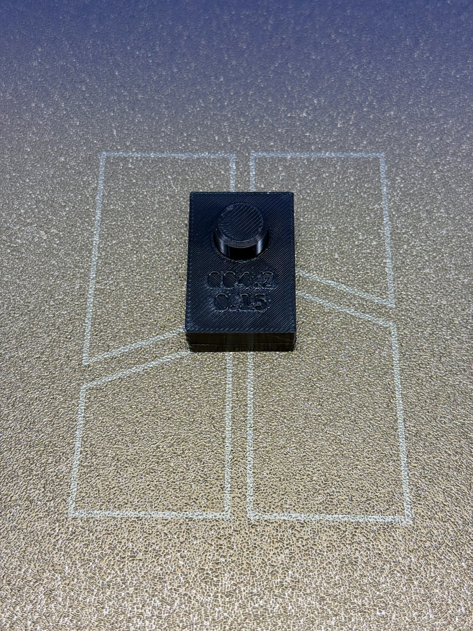 BRIM-004 iteration 2 assembled on the printer bed: the gauge block, debossed 004.2 and 0.15, seated on the peg plate with the dark PETG peg standing proud through the bore.