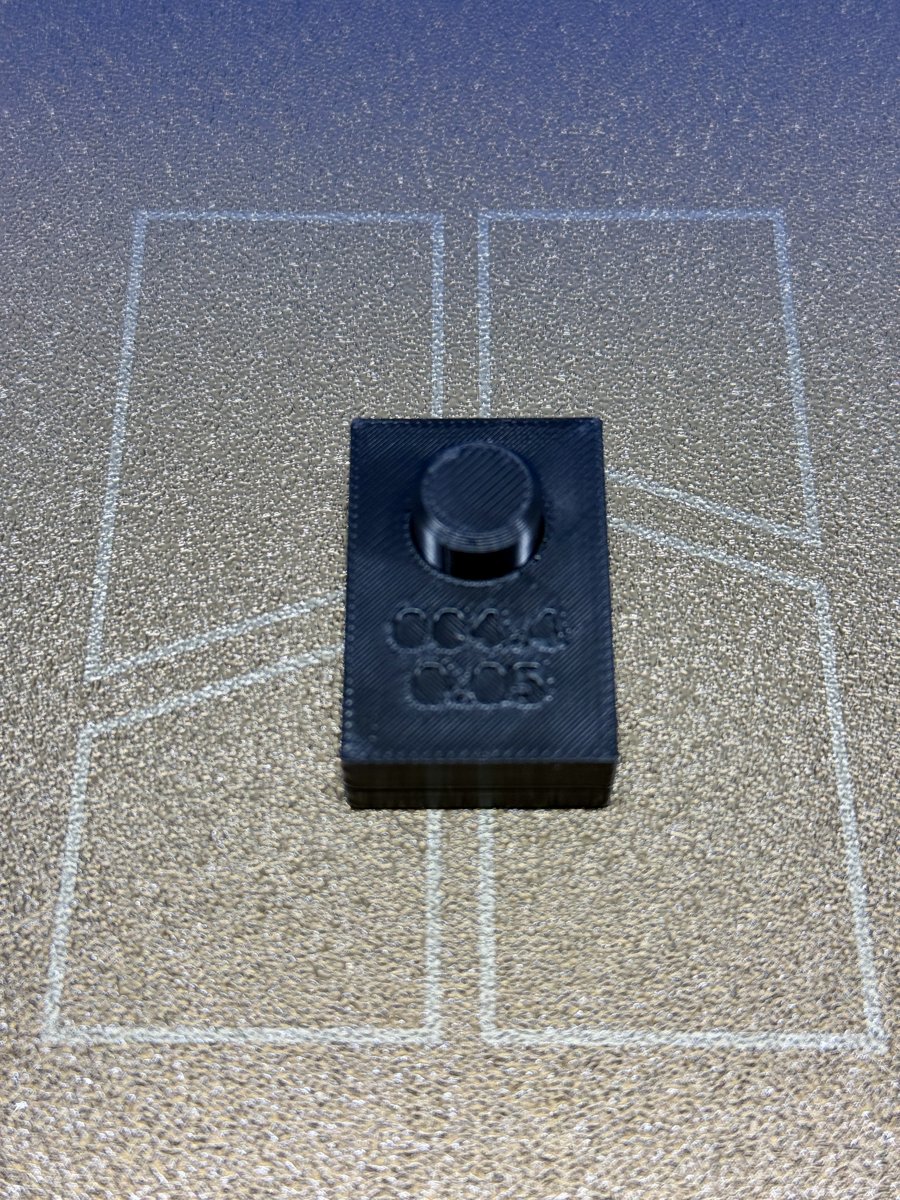 BRIM-004 iteration 4 assembled on the printer bed: the gauge block, debossed 004.4 and 0.05, seated on the peg plate with the dark PETG peg standing proud through the bore.